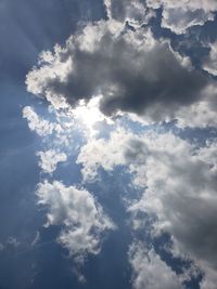 Low angle view of sunlight streaming through clouds