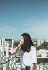 Woman standing by railing against sky