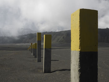 Wooden post on road against sky