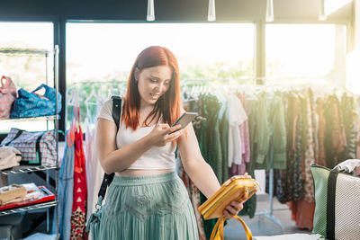 Portrait of young woman using mobile phone while standing in cafe