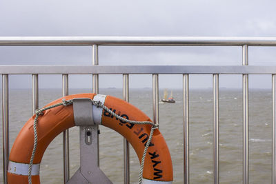 Close-up of railing by sea against sky