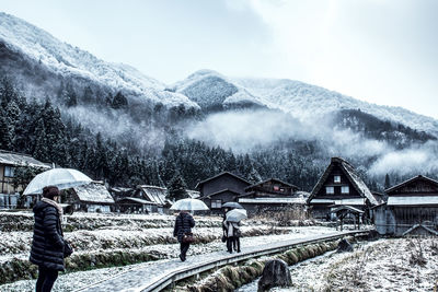 Rear view of people on snowcapped mountain against sky