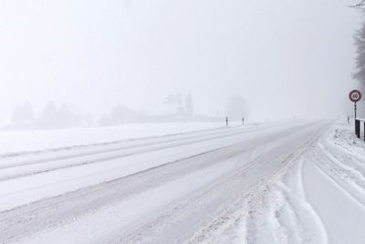 Snow covered road against sky during winter