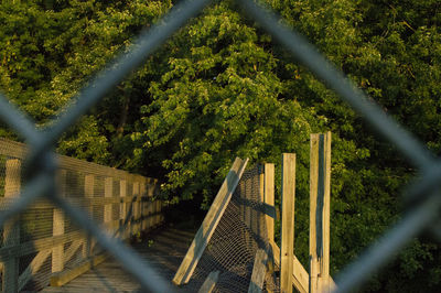 Chainlink fence by trees against sky