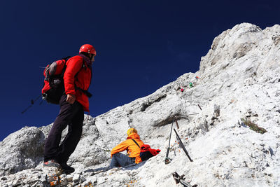 Low angle view of man climbing on rock against mountain