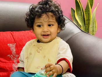 Portrait of cute girl sitting on sofa at home