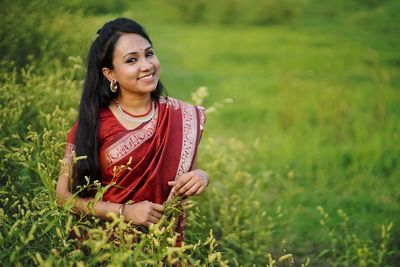 Portrait of smiling woman in sari standing by plants