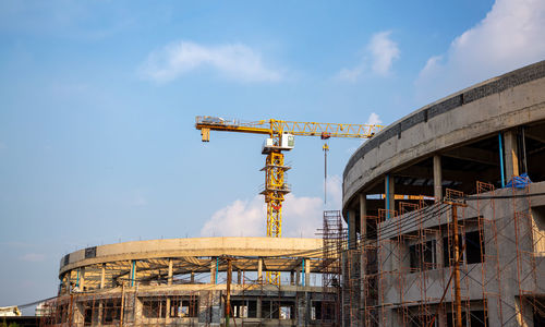 Low angle view of crane at construction site against sky