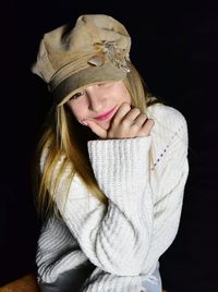 Smiling girl sitting against black background