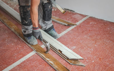 Human pulls out a nail from a board.