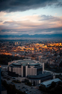 A cityscape in a green sunset, captured from a high vantage point with dramatic clouds 