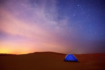 Tent on desert against sky during sunset