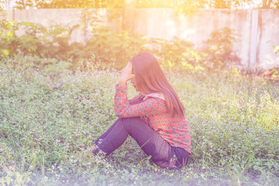 Side view of woman sitting on field