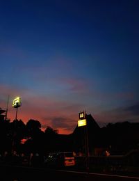 Cars on street against sky at sunset