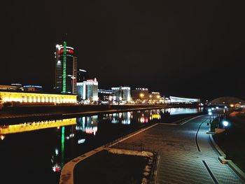 Illuminated bridge over river by buildings against sky at night