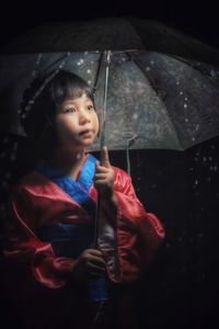 Cute boy looking away while standing in rain