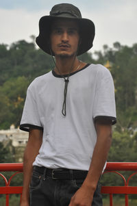 A indian young guy posing outdoor with wearing boonie hat and white tshirt and looking at camera 
