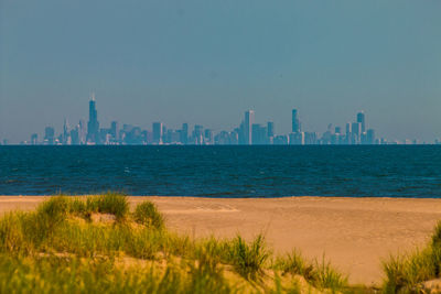 Scenic view of sea and buildings against clear sky