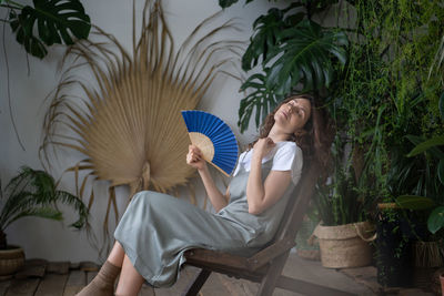 Relaxed calm woman enjoy spending time in indoor garden with working humidifier diffuser refreshing