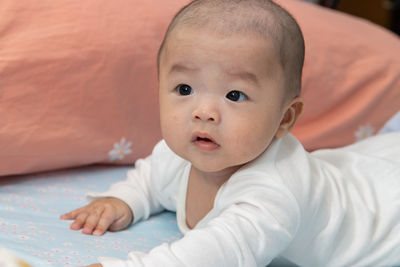 Portrait of cute baby lying on bed