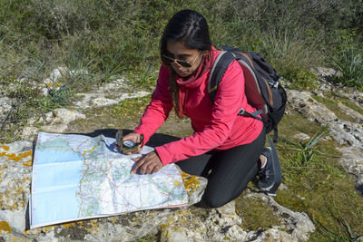 Young hikers sitting on the ground looking at an old map with a compass. hiking couple in nature,