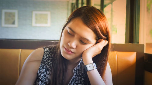 Close-up of beautiful young woman sitting with eyes closed