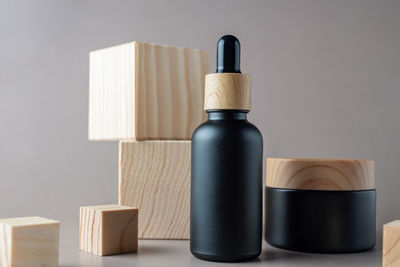 Black cosmetic dropper bottle and cream jar mockup on wooden cubes. herbal cosmetics branding