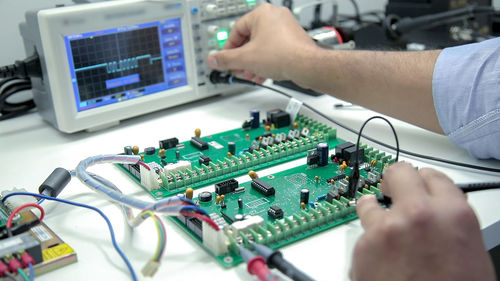 Cropped hands of worker examining mother board