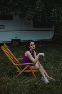 Portrait of woman sitting on seat in field