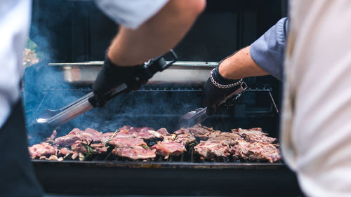 Midsection of man preparing food on barbecue grill