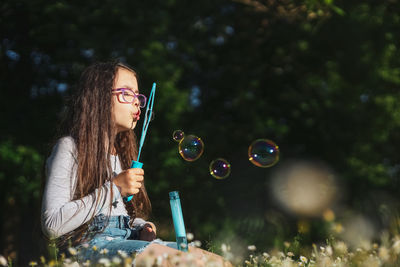 Portrait of young woman blowing bubbles