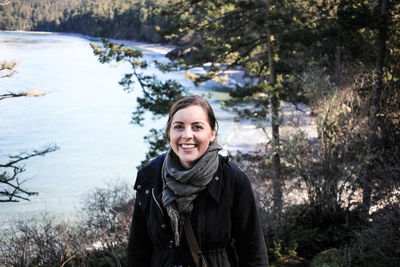 Portrait of smiling woman by lake during winter