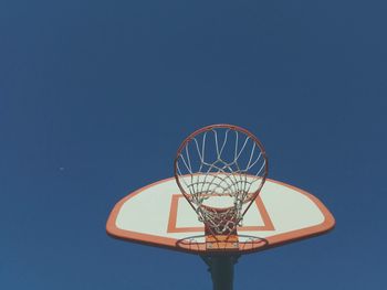 Low angle view of basketball hoop against clear blue sky