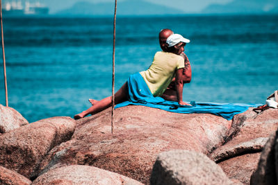 Rear view of man on rock at sea shore