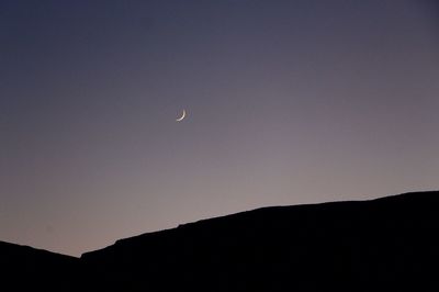 Low angle view of silhouette moon against clear sky at night