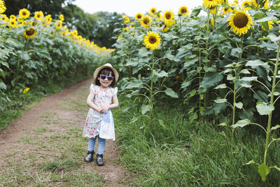Portrait of girl standing on flowering plants