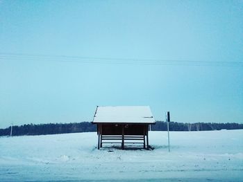 Lifeguard hut on snow covered landscape against clear sky