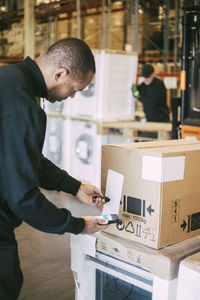 Male entrepreneur scanning with bar code reader through smart phone at warehouse