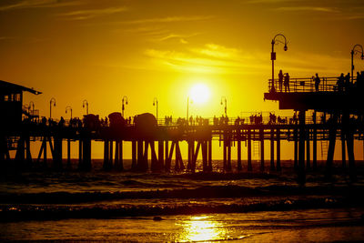 Silhouette pier over sea against sky during sunset