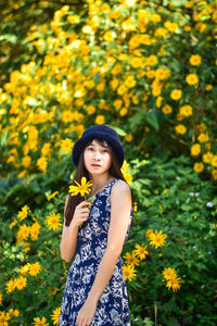 Portrait of woman standing on yellow flowering plants