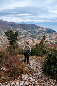 Rear view of man standing on mountain against sky