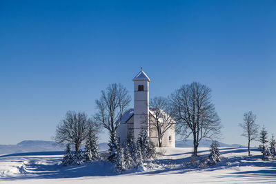 Built structure on snow covered landscape against blue sky