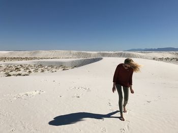 Full length of woman standing on sand at desert against clear sky