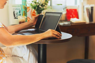 Midsection of woman using laptop at home