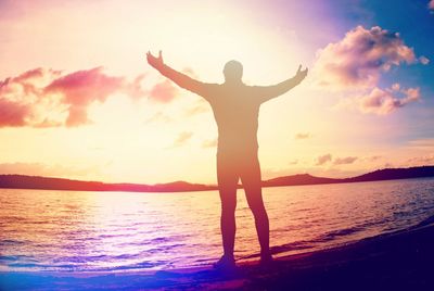 Man raising arms on sea shore. happy man raised hands above head on beach. abstract light