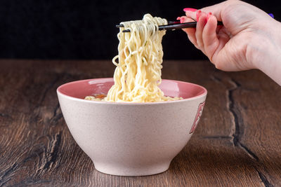 Cropped hand of person preparing food in bowl on table