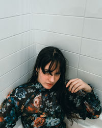 Portrait of beautiful young woman against tiled wall in bathroom