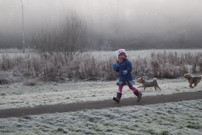 Full length of boy running on snow covered landscape