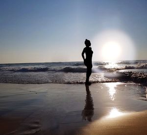 Silhouette man standing on beach against clear sky