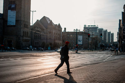 Rear view of man walking on road in city